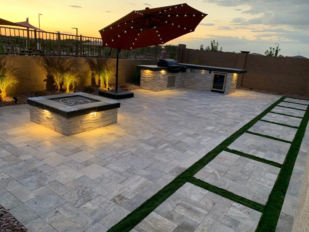 Modern backyard hardscape featuring a built-in firepit, outdoor kitchen, and travertine patio