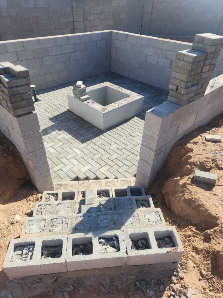 Block fire pit under construction with paver flooring and cinder block walls