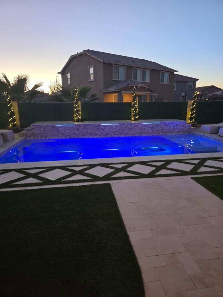 Modern backyard pool with blue lighting and illuminated palm trees