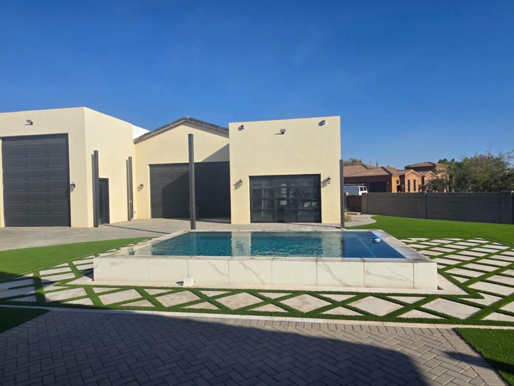 Modern backyard pool with marble-style tile, turf accents, and geometric hardscape