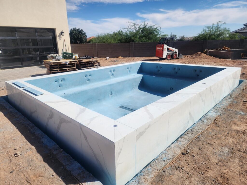 Pool construction showing blue interior shell and marble coping