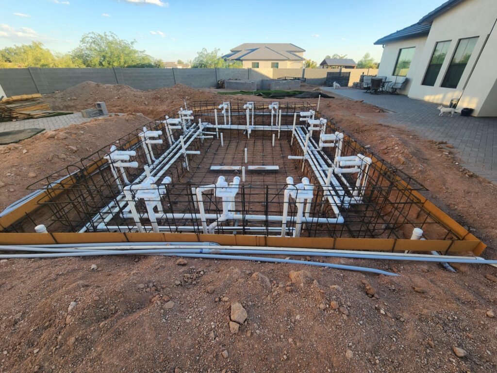 Reinforced rebar and PVC piping grid before gunite application in backyard pool build