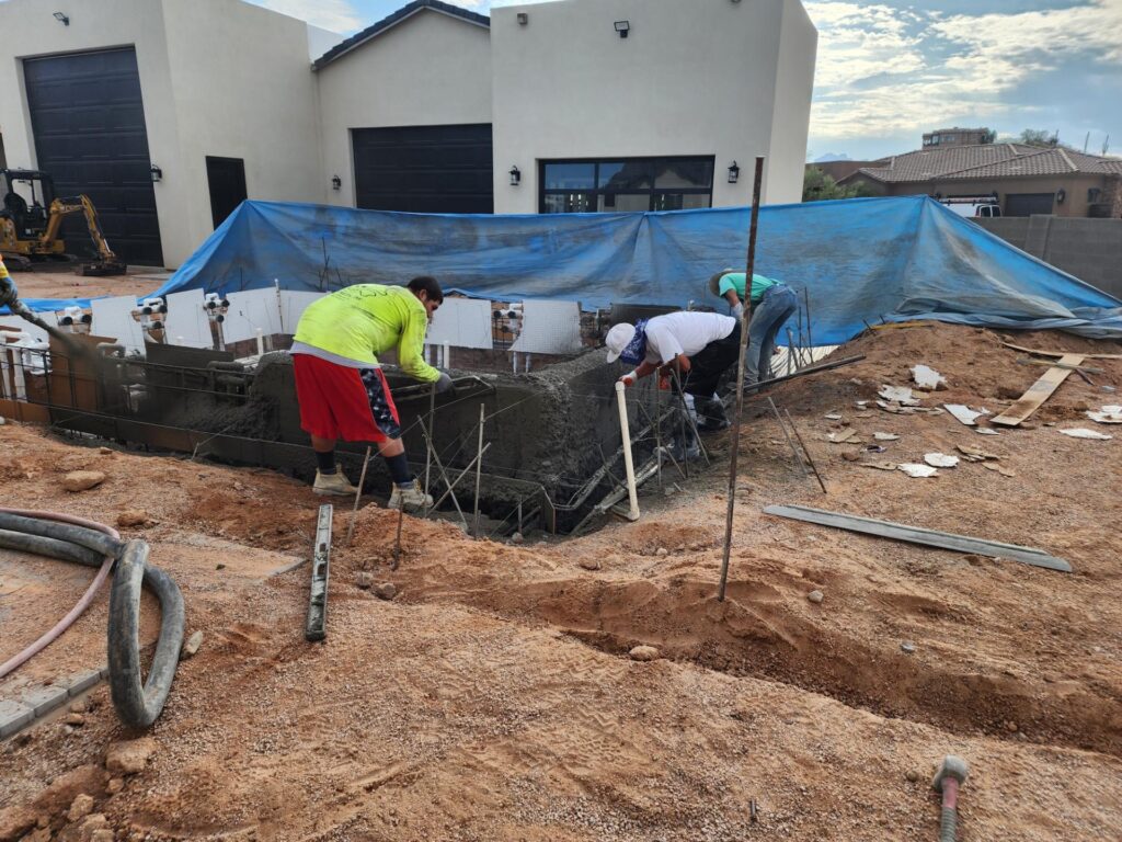 Aqua Squad crew applying shotcrete during pool construction in backyard