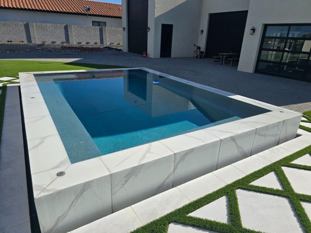Raised modern pool installation with marble-style tile finish