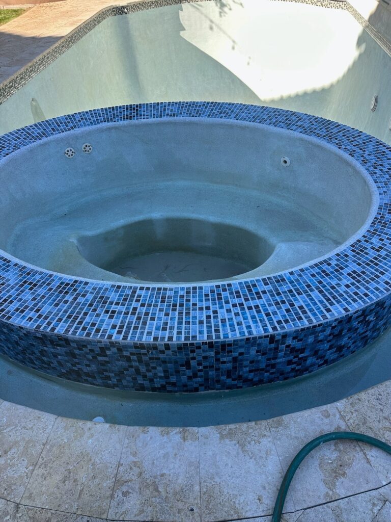 Raised spa remodel featuring blue glass tile and light stone coping