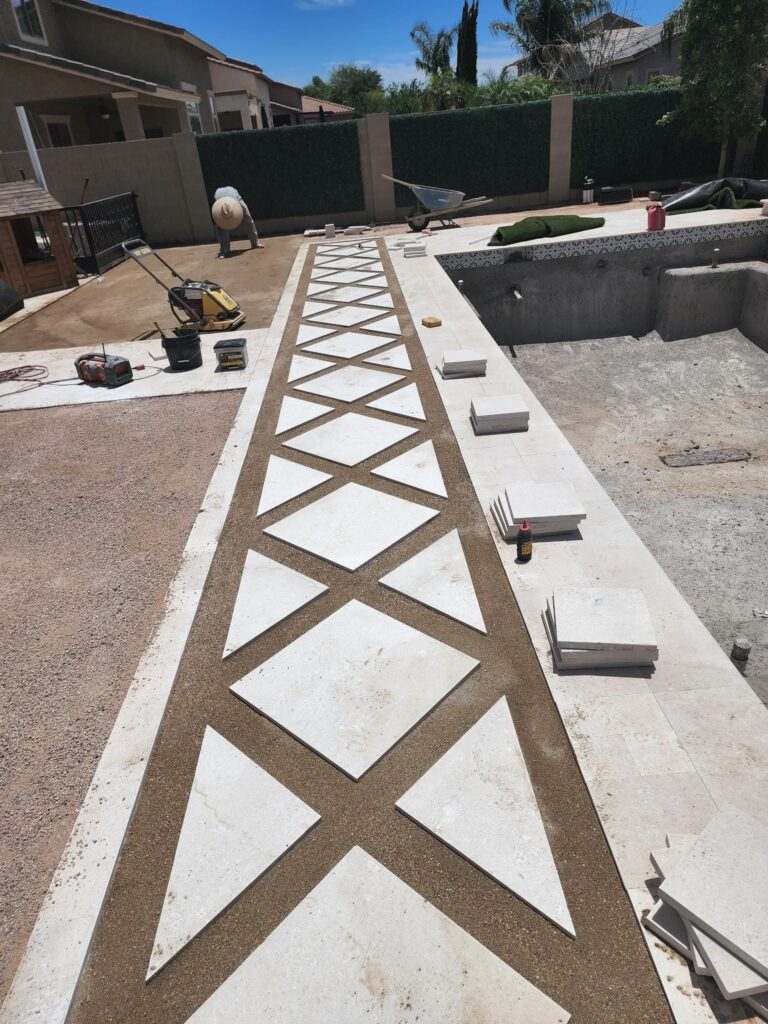 Installing geometric travertine walkway beside new pool project