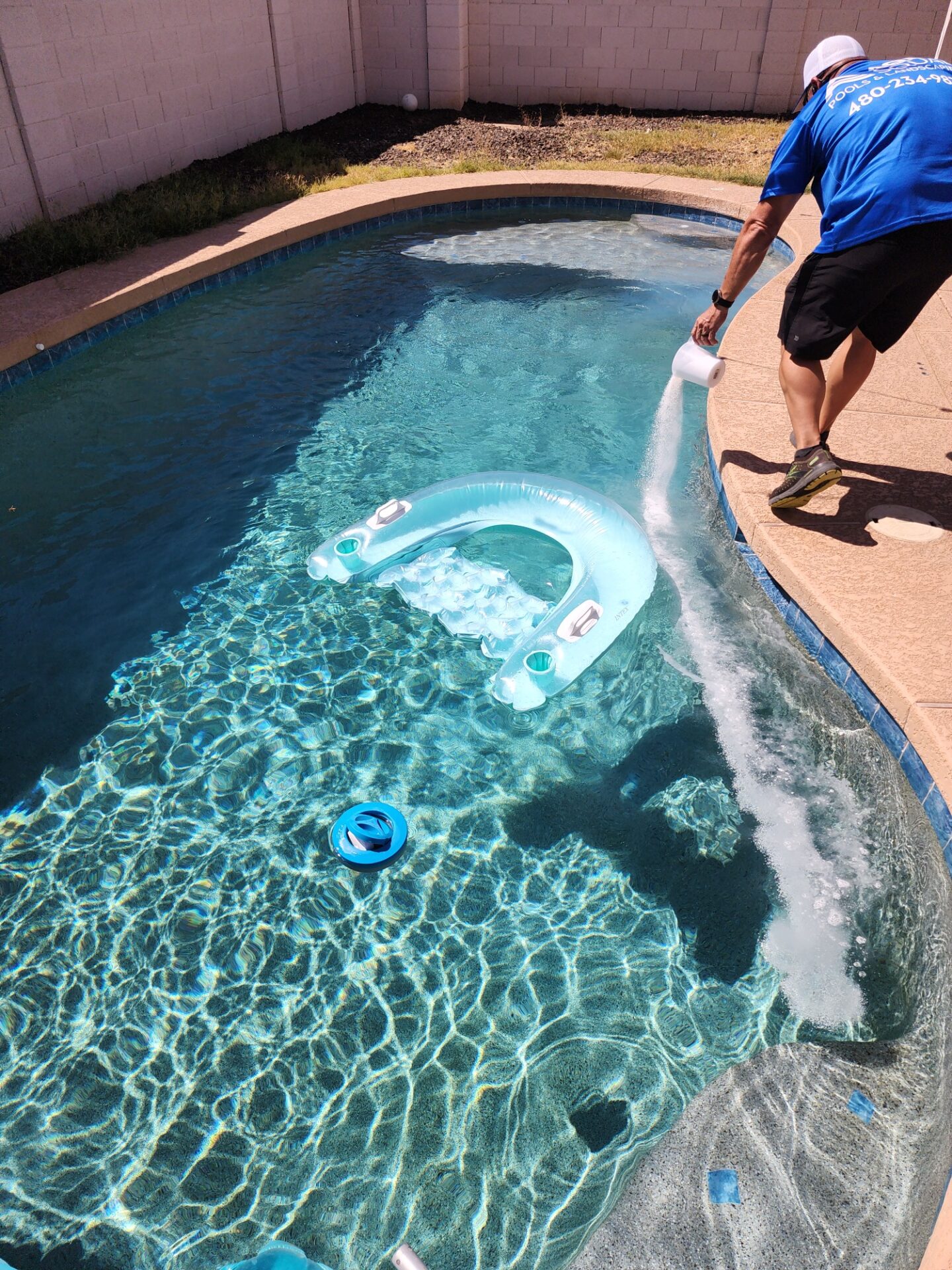 Aqua Squad technician adding pool shock treatment during weekly service