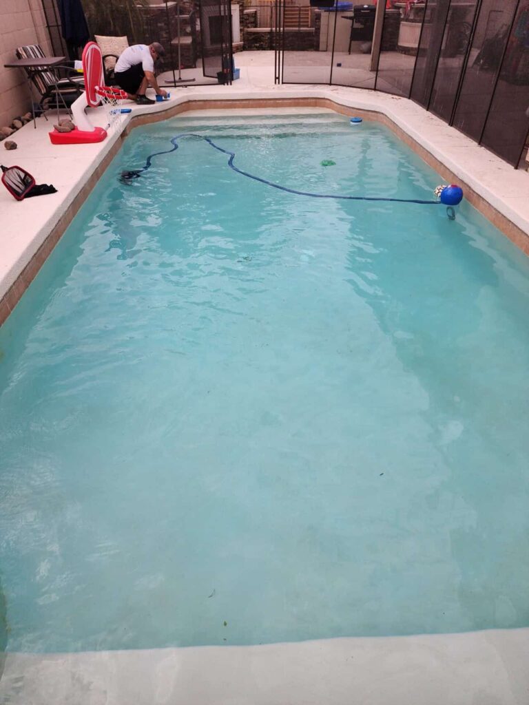 Pool technician testing and balancing water chemistry during cleaning service in Mesa