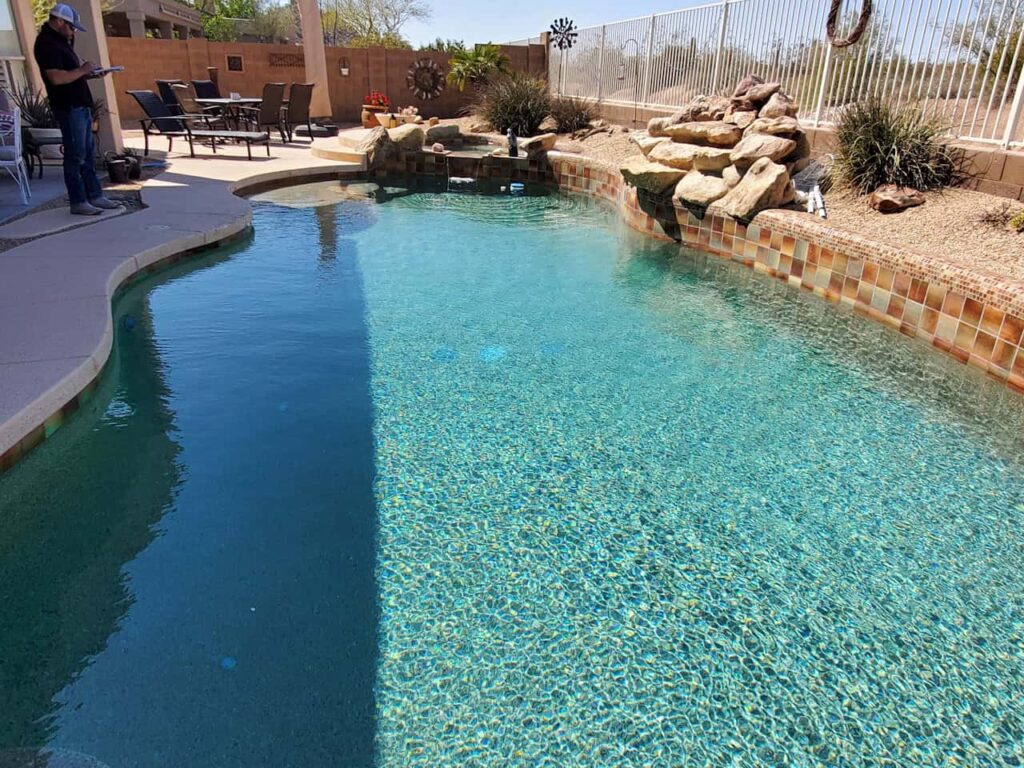 clear residential backyard pool with rock waterfall feature